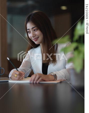 Female office worker working with stationery on table in office room 69935741
