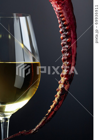 Grilled octopus and white wine glass on a black background. 69936911