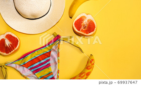 Grapefruit, banana, traw hat and a bright swimsuit on a yellow background 69937647