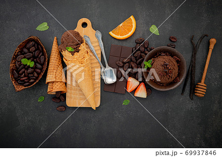 Chocolate ice cream flavours in bowl with dark chocolate and cacao nibs setup on dark stone background . Chocolate ice cream flavours in bowl with dark chocolate and cacao nibs setup on dark stone background . 69937846