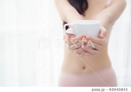 Closeup young asian sexy woman in underwear giving coffee near windows in the morning. 69940843