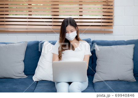 Young asian business woman in face mask work from home on laptop computer. 69940846