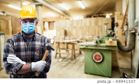 Carpenter at work protects the face with the surgical mask. Carpentry. Covid-19 prevention. 69941337