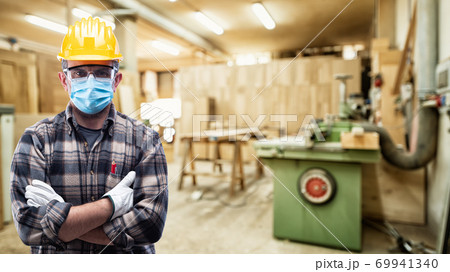 Carpenter at work protects the face with the surgical mask. Carpentry. Covid-19 prevention. 69941340