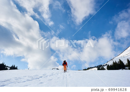 Skier tourist with backpack on background of bright blue sky and beautiful mountain panorama. 69941628