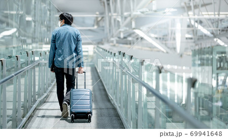 Asian man tourist wearing mask in airport terminal Asian man tourist wearing mask in airport terminal 69941648