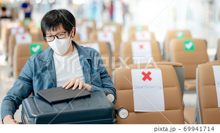 Asian man tourist opening suitcase in airport terminal Asian man tourist opening suitcase in airport terminal 69941714