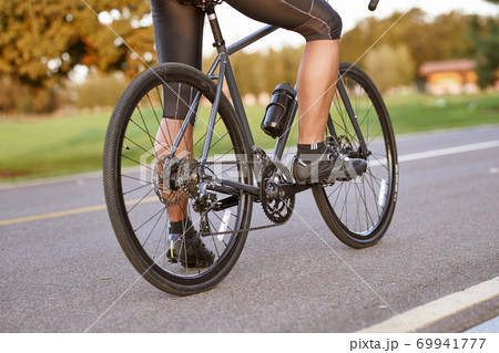 Biking outdoors. Cropped shot of a man cycling outdoors, standing with his bycicle on the road. Focus on male legs Biking outdoors. Cropped shot of a man cycling outdoors, standing with his bycicle on the road. Focus on male legs 69941777