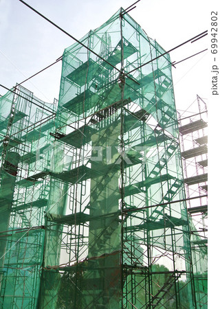 SELANGOR, MALAYSIA -AUGUST 4, 2020: Temporary stairs and scaffolding are used in the construction of high concrete columns. Scaffolding is wrapped with safety netting for safety purposes. 69942802