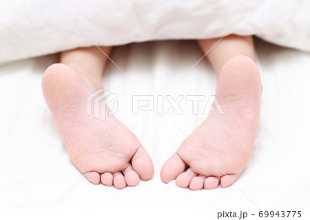 ベッドで眠る女の子の素足の写真素材