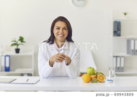 Happy female dietician sitting at her desk in office looking at camera and smiling 69943809