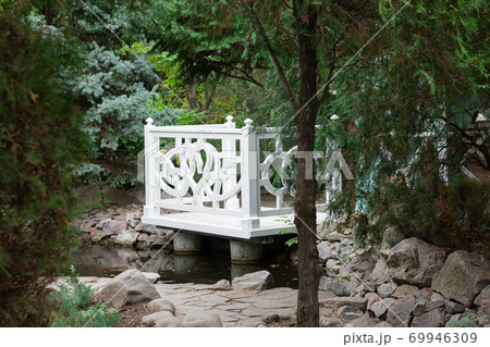 White wooden gazebo in a summer green park. Cozy garden alcove to spend time 69946309