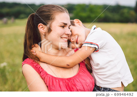 Mother and son hugging in field. Happy mother embracing her son in park. Mother hugging her child. Motherhood. Young mother cuddle her happy baby in fields at sunset. Lovely little kid Mother and son hugging in field. Happy mother embracing her son in park. Mother hugging her child. Motherhood. Young mother cuddle her happy baby in fields at sunset. Lovely little kid 69946492