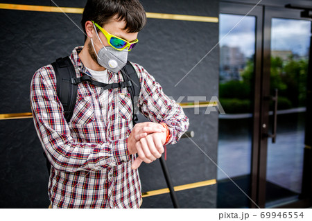 Male courier wearing protective face mask arrived at delivery address on electric scooter. Subject delivery during covid 19 on environmentally friendly transport. Pollution in big city. PM 2.5 mask 69946554