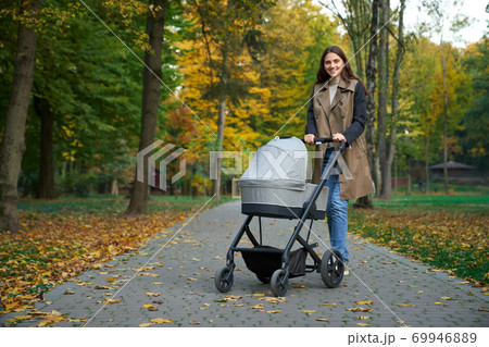Young mother in park with newborn posing at camera. 69946889