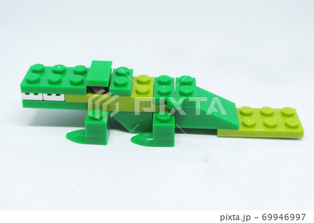 The shape of a green crocodile is made from colorful plastic toy bricks. 69946997