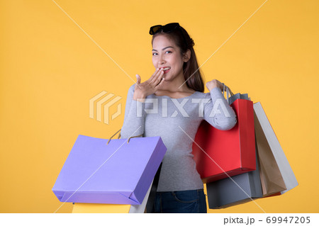 Young Asian woman with colourful shopping bags and credit card isolated on yellow background 69947205