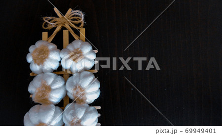Fresh harvesting garlic tied in bunches. Dried decorative garlic on the dark background Fresh harvesting garlic tied in bunches. Dried decorative garlic on the dark background 69949401