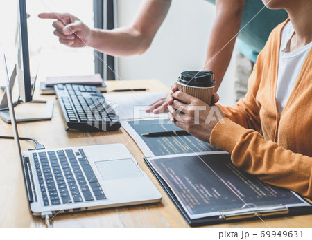 Two professional programmer cooperating and working on web site project in a software developing on desktop computer at company, codes and typing data code, Programming with HTML, PHP and javascript 69949631