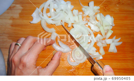 Raw sliced white onion on wooden chopping board ready to cook 69950405