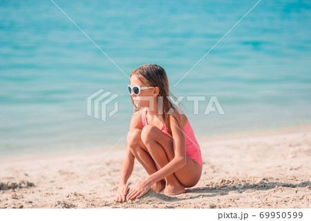 Adorable little girl have fun at tropical beach during vacation Adorable little girl have fun at tropical beach during vacation 69950599