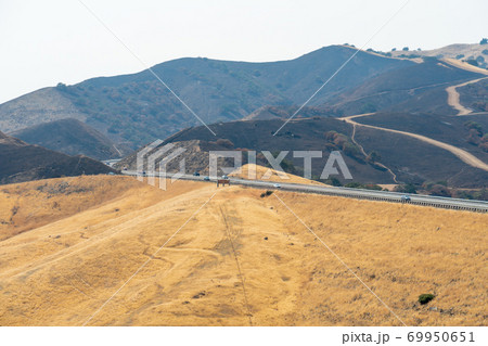 Freeway road crossing the the San Luis Reservoir valleys during dry and hot season, California, USA 69950651