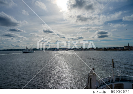 Ocean view towards Elsinore in Denmark from the aft of a boat. Backlit picture with blue ocean and blue sky Ocean view towards Elsinore in Denmark from the aft of a boat. Backlit picture with blue ocean and blue sky 69950674