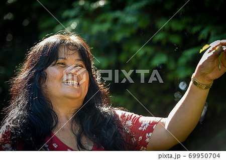 Closeup picture of a middle-aged, in her 50s, Asian woman with soap bubbles. Green background Closeup picture of a middle-aged, in her 50s, Asian woman with soap bubbles. Green background 69950704