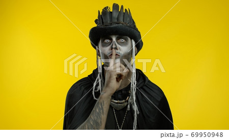 Creepy man with skeleton makeup asking to stay calm, keep silence with finger on lips gesture Creepy man with skeleton makeup asking to stay calm, keep silence with finger on lips gesture 69950948