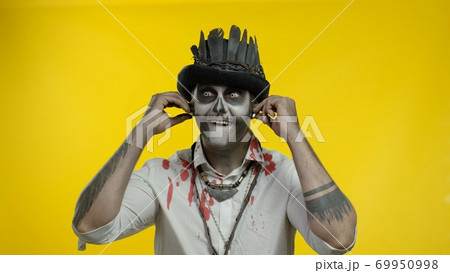 Sinister man with horrible Halloween skeleton makeup puts on headphones, starts dancing, celebrating Sinister man with horrible Halloween skeleton makeup puts on headphones, starts dancing, celebrating 69950998