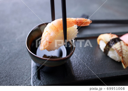 Chopsticks dipping prawn nigiri sushi into sauce 69951008