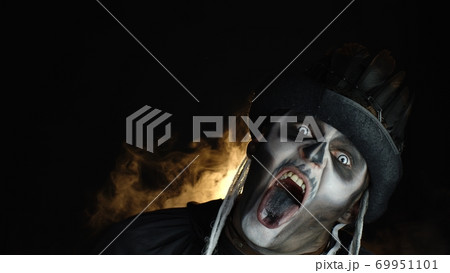 Creepy, crazy man with skeleton makeup. Guy making angry faces, shaking head, showing tongue Creepy, crazy man with skeleton makeup. Guy making angry faces, shaking head, showing tongue 69951101