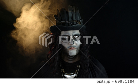 Creepy man with skeleton makeup in top-hat. Guy making faces, toothy smile. Halloween thematic party 69951184