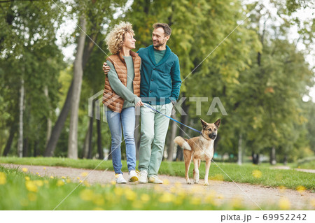 Couple walking with dog Couple walking with dog 69952242