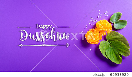 Happy Dussehra. Yellow flowers, green leaf and rice on purple pastel background. Dussehra Indian Festival concept. 69953929