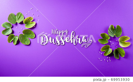 Happy Dussehra. Green leaf and rice on purple pastel background. Dussehra Indian Festival concept. Happy Dussehra. Green leaf and rice on purple pastel background. Dussehra Indian Festival concept. 69953930