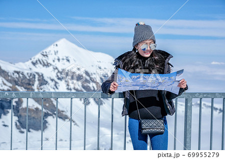 woman looking map at the Schilthorn in Switzerland with a panoramic view of the Swiss Skyline. woman looking map at the Schilthorn in Switzerland with a panoramic view of the Swiss Skyline. 69955279