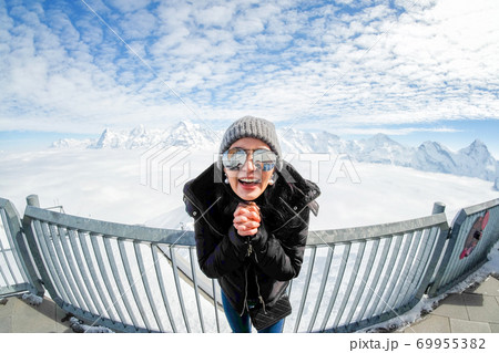 Woman Tourist at Schilthorn in Switzerland with a magnificent panoramic view of the Swiss Skyline. Woman Tourist at Schilthorn in Switzerland with a magnificent panoramic view of the Swiss Skyline. 69955382