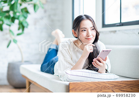 リビングでスマホを使う若い女性 リビングでスマホを使う若い女性 69958230