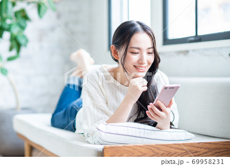 リビングでスマホを使う若い女性 69958231