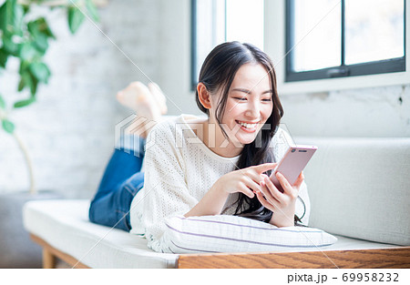 リビングでスマホを使う若い女性 69958232