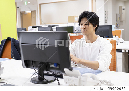 机で一人でディスクワークをする若い男性 69960072