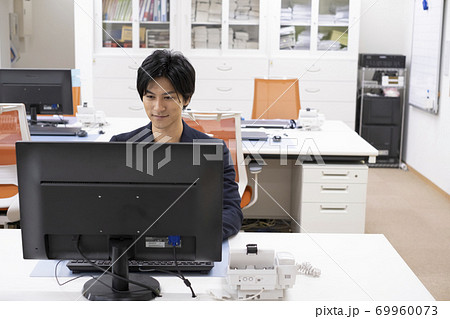 机で一人でディスクワークをする若い男性 69960073