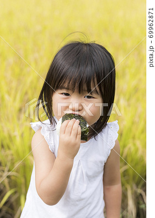 稲穂の実った秋の田んぼで美味しい新米おにぎりを食べる子供 稲穂の実った秋の田んぼで美味しい新米おにぎりを食べる子供 69962871