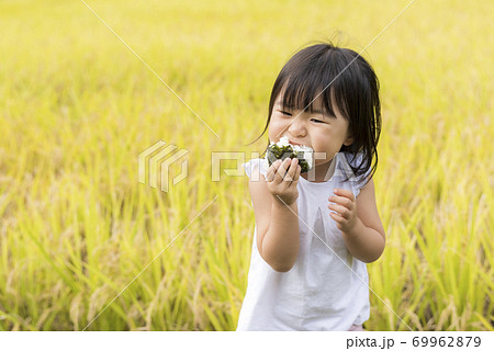 稲穂の実った秋の田んぼで美味しい新米おにぎりを食べる子供 稲穂の実った秋の田んぼで美味しい新米おにぎりを食べる子供 69962879
