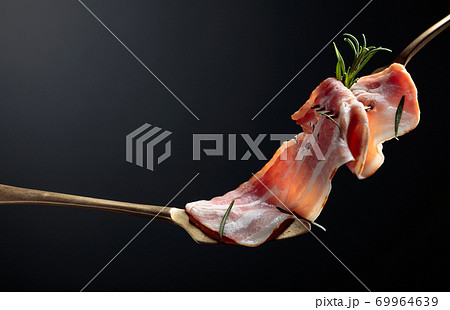 Bacon slices and rosemary on a fork. Bacon slices and rosemary on a fork. 69964639