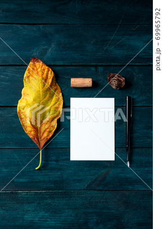 Autumn stationery mockup, a vertical A5 greeting card or invitation, shot from the top on a dark blue wooden background with a wine cork Autumn stationery mockup, a vertical A5 greeting card or invitation, shot from the top on a dark blue wooden background with a wine cork 69965792