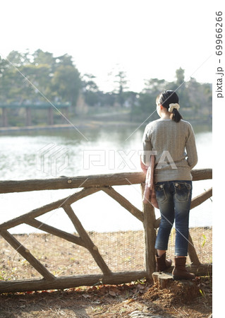 公園の池の前に立つ女性 69966266
