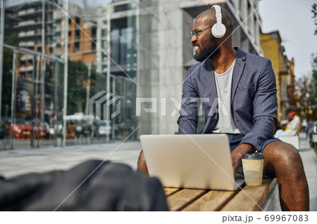 Relaxed international freelancer looking at business center Relaxed international freelancer looking at business center 69967083