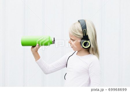 Young blond girl on white background drink fresh spring water from green reusable bottle 69968699